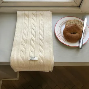 Nahaufnahme des weissen Zopfmuster Winter Schals Textur auf einer hellen Fensterbank.