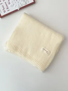 Detailansicht des dicken warmen Strickschals im Winter in sanfter Cremefarbe mit Struktur.