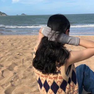 Detailansicht der grauen Strickhandschuhe mit modischen Streifen am schönen Strand.
