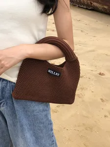 Detailaufnahme einer braunen gestrickten Dumpling-Handtasche mit gewebter Textur und Etikett.