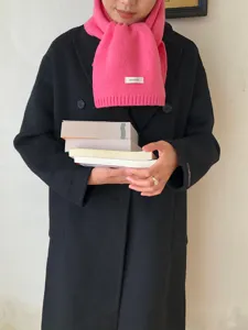 Detailaufnahme des hellrosa Winter-Strickwollschals, getragen vom Modell mit Büchern.