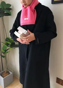 Nahaufnahme Detailansicht des kuscheligen rosa Winterstrickschals mit schwarzem Mantel.