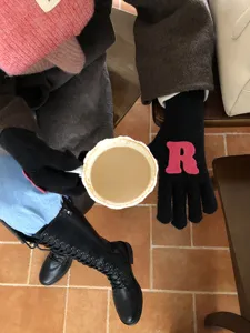 Detailaufnahme von Winter-Strickhandschuhen mit rosa Buchstaben-Aufnäher, weich und warm.