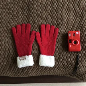Red knitted winter gloves with plush cuffs detail shot, warm wool thermal touchscreen mittens.