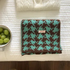 Primo piano della sciarpa in maglia pied-de-poule verde e marrone con etichetta chic.