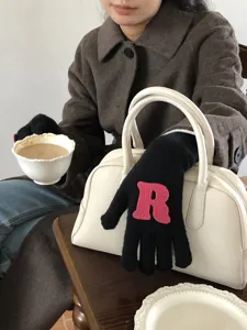 Detailansicht schwarzer Strickhandschuhe mit rosa R-Buchstabe, weiches Winter-Warm-Accessoire.