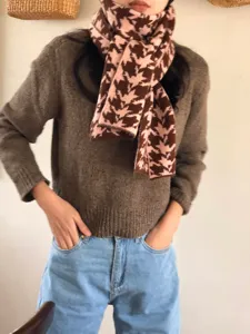 Dettaglio della sciarpa in maglia pied-de-poule marrone e rosa, accessorio invernale.