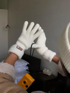 Close-up of white knitted winter gloves with cozy fleece cuff detail, warm fabric.