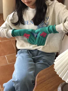 Nahaufnahme von warmen Winter-Knitted-Handschuhen mit Buchstaben-Patch in gemütlicher Szene