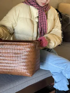 Detail shot of a stylish pink and brown houndstooth knitted scarf worn by a model indoors.