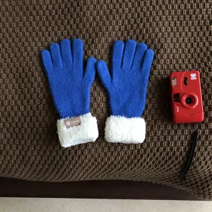 Blue knitted gloves with white plush cuffs detailed shot, warm winter knitwear item.
