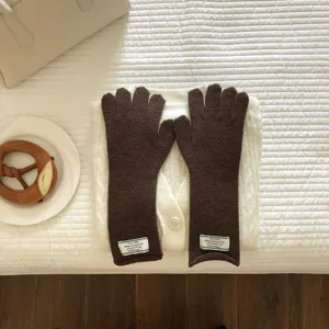 Nahaufnahme gemütlicher dunkelbrauner Winter-Strickhandschuhe im stilvollen Flat-Lay-Stil.
