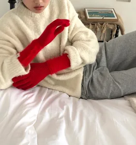 Nahaufnahme der kuscheligen langen roten Strickhandschuhe im Schlafzimmer, weiche Textur.