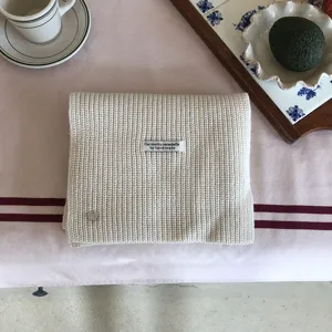 Nahaufnahme Detail des minimalistischen beigen Strickschals mit handgefertigtem Etikett im Winter.