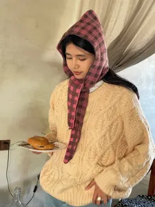 Close-up view of the pink plaid knitted hood scarf showing soft textured fabric details in indoor scene.