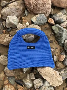 Nahaufnahme einer blauen Damen Stricktasche im modernen Stil auf natürlichen Steinen.