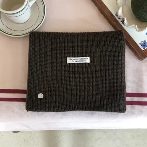 Detailansicht eines kuscheligen dunkelbraunen Strickschals mit handgemachtem Etikett.