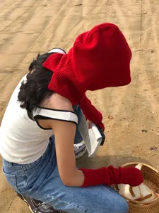 Detailed view of cozy red knitted arm warmers and matching balaclava hood, outdoor lifestyle style.