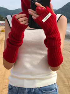 Detail view of red knit arm warmers and long fingerless gloves made of warm wool material.