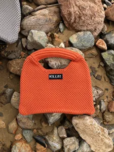 Nahaufnahme Detail der leuchtend orangefarbenen Stricktasche mit strukturierter Handtasche.