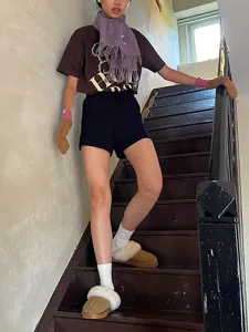 Detailed shot of a stylish purple winter wool fringe scarf worn by a model on indoor stairs.