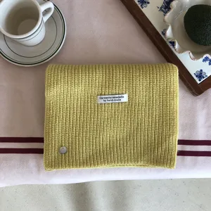 Gemütlicher Wollemix Strickschal Detail mit weicher gelber Textur und handgemachtem Etikett.