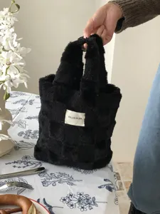 Detailed view of black plush checkered handbag, cozy winter fuzzy tote bag texture closeup.