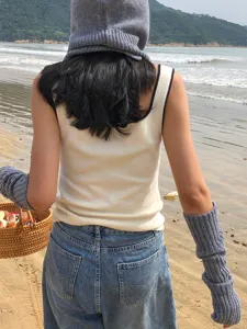Detailed view of winter knitted arm warmers and matching beanie hat in casual beach setting.
