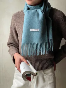 Detail shot of light blue wool winter scarf with fringe, soft warm solid color design.