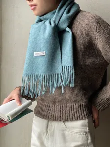 Close-up detail of the cozy winter wool scarf featuring soft fringe and 100% wool material tag.