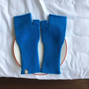 Detailaufnahme von einfarbigen blauen Strick-Fingerling-Handschuhen mit gerippten Bündchen.