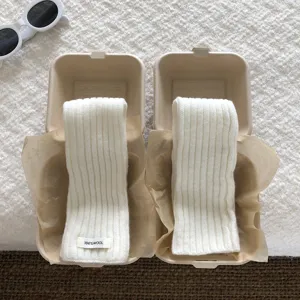 Detail view of cozy white wool knit arm warmers presented in creative eco paper boxes.