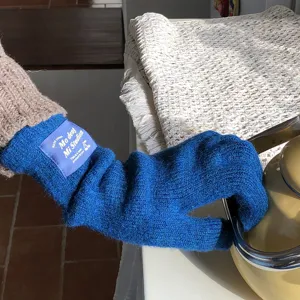 Detailaufnahme der dicken blauen Strickhandschuhe mit gewebtem Label am Handgelenk zum Zeigen