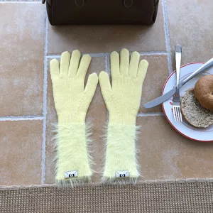 Detailaufnahme langer gelber Strickhandschuhe mit flauschigen Bündchen, stilvoll für den Winter.