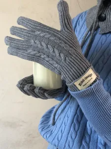 Close-up of grey cable knit gloves showing the textured pattern and woven wrist label.