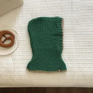 Green knitted contrast color balaclava hooded scarf winter warm hat detail shot.