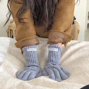 Nahaufnahme von grauen Strickhandschuhen mit Rippbündchen und gemütlichem Fingerdesign.