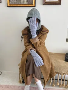 Close-up detail of cozy grey knitted balaclava hat and warm winter gloves in lifestyle scene.