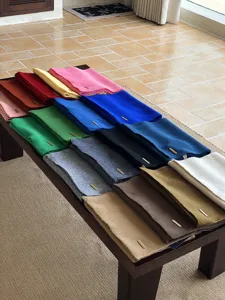 Detailansicht luxuriöser Wollschals in vielen bunten Farben auf stilvollem Holztisch präsentiert.