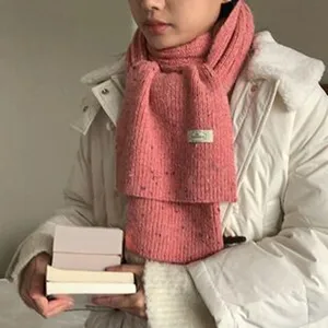 Primo piano di una calda sciarpa invernale in maglia rosa con macchie colorate, morbida.