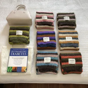 Vista di dettaglio di sciarpe in mohair a righe colorate disposte con borsa e accessori.