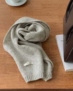 Gedetailleerd overzicht van een zachte wollen gebreide sjaal in havermoutkleur.