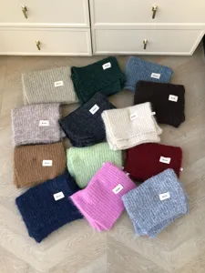 Nahaufnahme flach ausgelegter, flauschiger Mohair-Strickschals in vielen Farben, kuschelig warm.