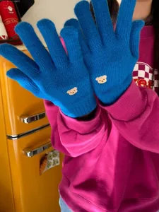 Dettaglio dei guanti in maglia ricamati con grazioso orsetto per il freddo invernale.