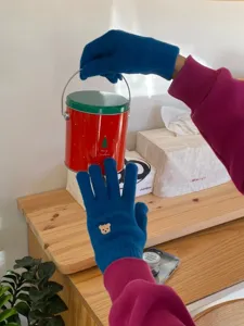 Primo piano di guanti in maglia blu con ricamo di orsetto, consistenza morbida e stile.