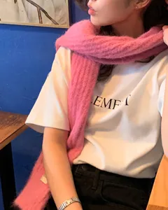 Nahaufnahme eines weichen, einfarbigen rosa Mohair-Schals kombiniert mit weißem Shirt.