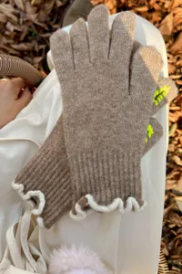 Close-up detail of women winter knit touchscreen gloves with elegant ruffled cuffs and wool blend.