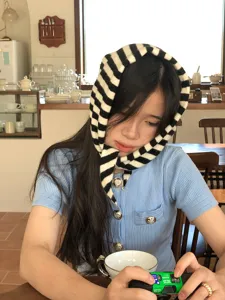 Gedetailleerd overzicht van de zwart-wit gestreepte gebreide driehoekssjaal in café.
