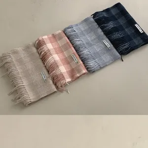 Detailaufnahme von vier karierten Wollschals in Beige, Rosa, Blau und Dunkelblau mit Fransen.