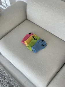 Detailansicht bunter Strickhandschuhe mit niedlichen Schleifen, ordentlich auf Sofa.